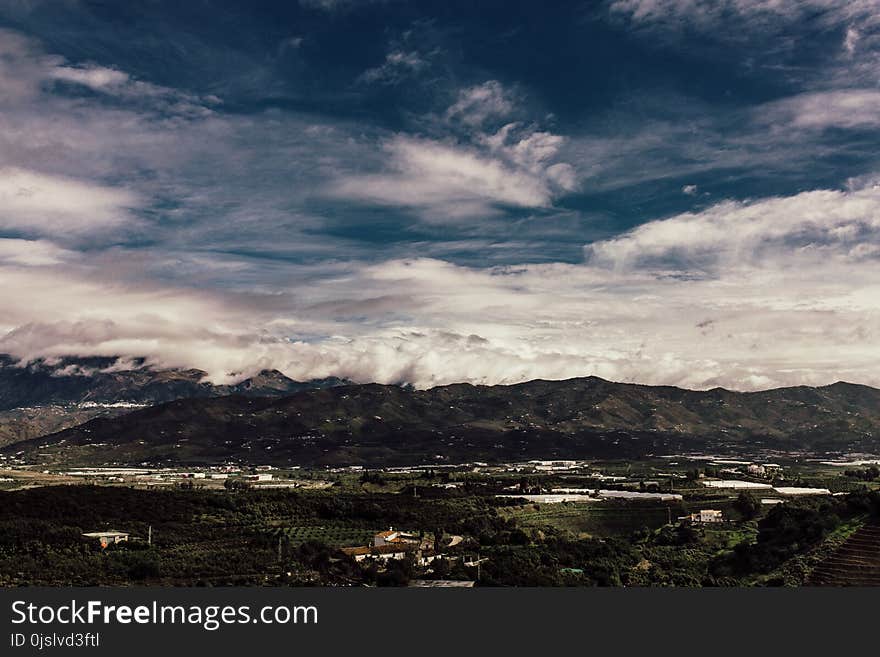 Aerial Photography of Grass Field Near Mountain Under White Cloudy Sky