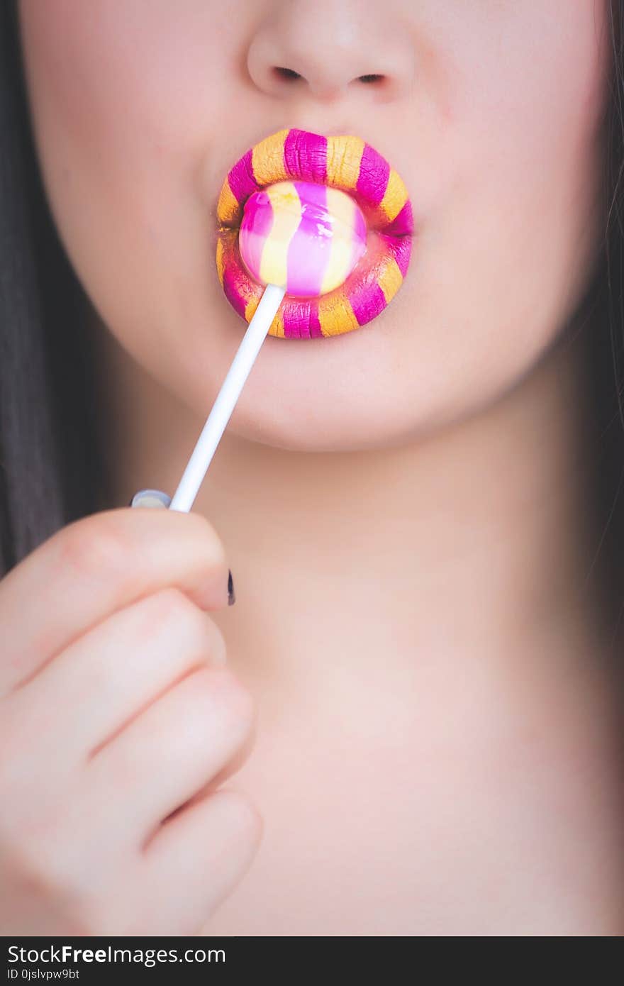 Woman With Yellow and Pink Lipstick Eating LolliPop