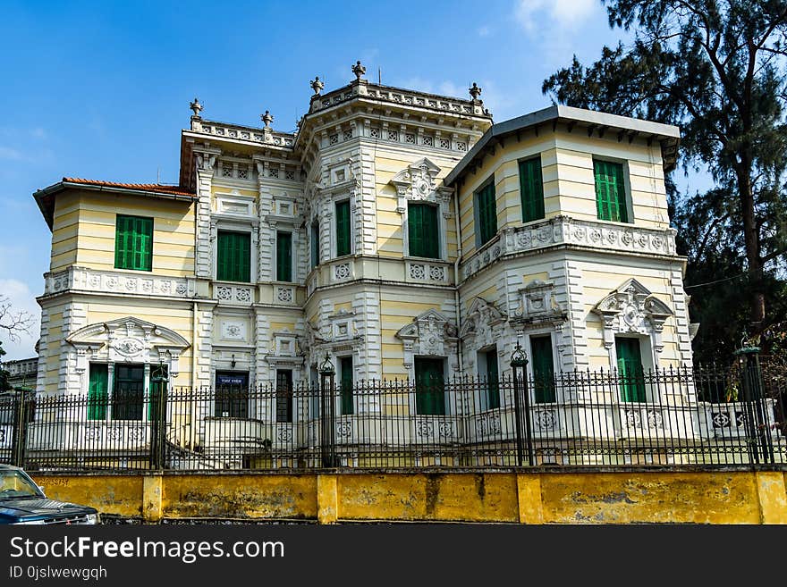 Yellow and White Painted Mansion Near Black Iron Gate