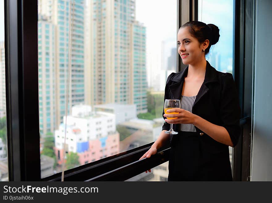 Beautiful business woman smile and standing at the window with champagne. Beautiful business woman smile and standing at the window with champagne