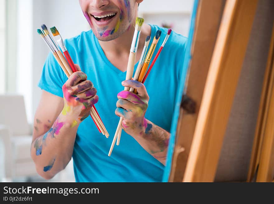 The young funny artist working on new painting in his studio