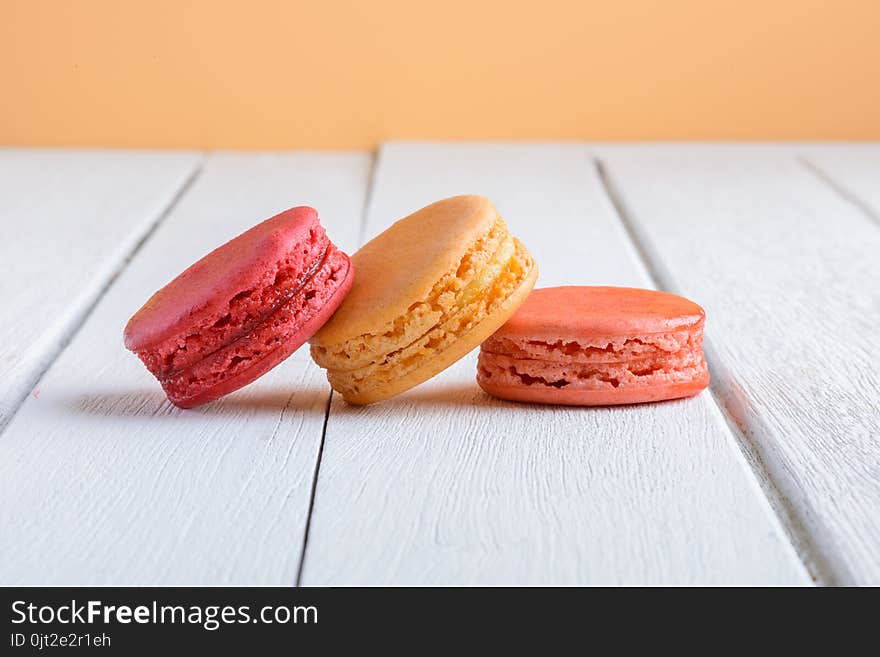 Different types color of macaroons on white wooden background Vintage style