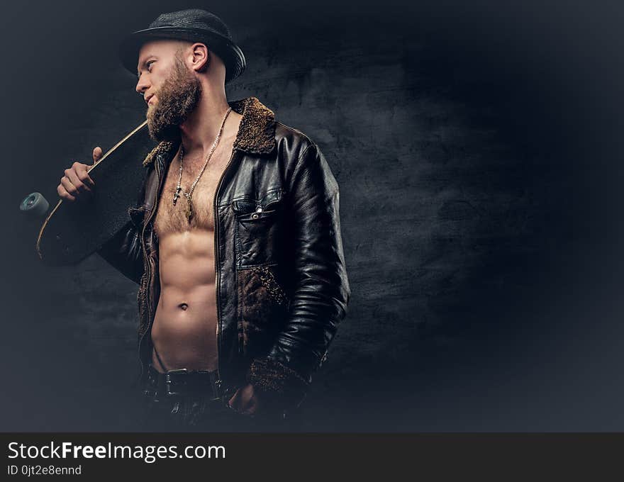 Bearded Male Dressed In Leather Jackett Holds Skateboard.