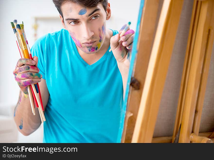 The young funny artist working on new painting in his studio