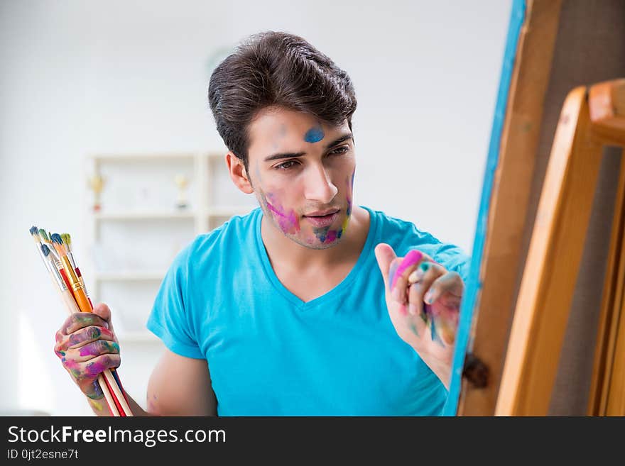 The young funny artist working on new painting in his studio