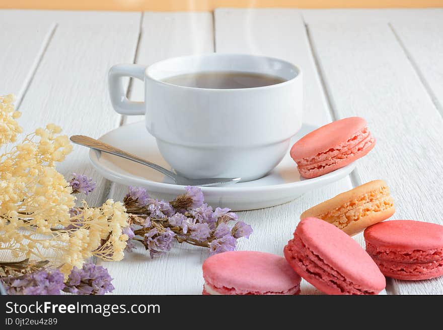 Different types color of macaroons with Cup of hot tea on white