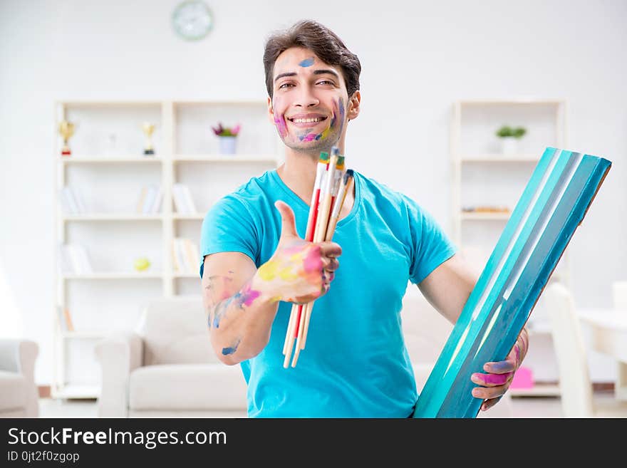 The young funny artist working on new painting in his studio