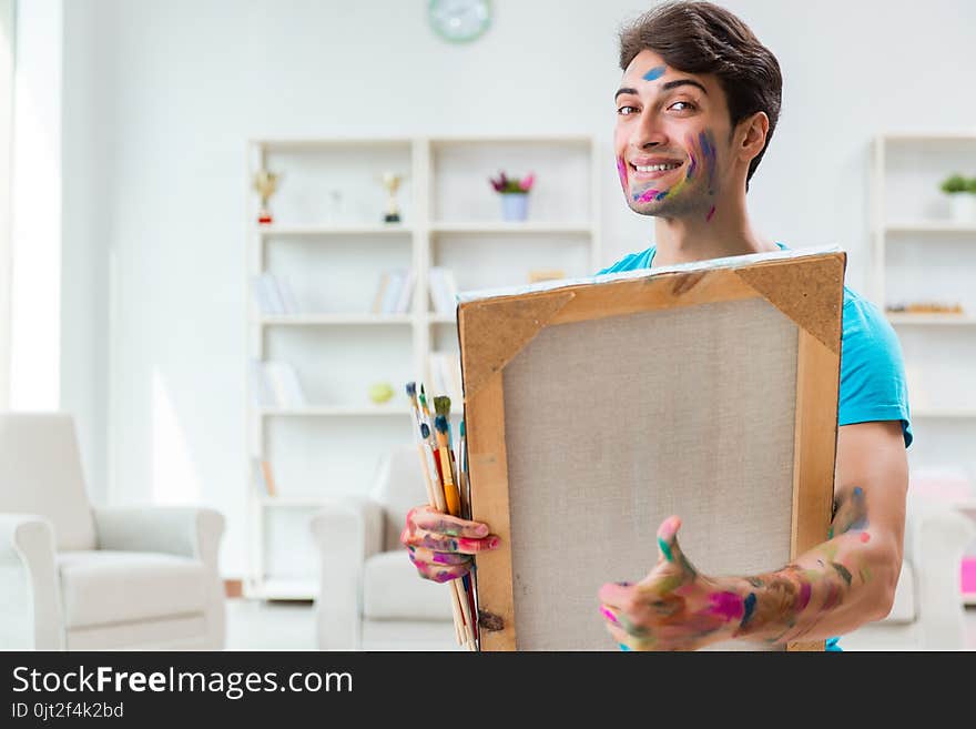 The young funny artist working on new painting in his studio