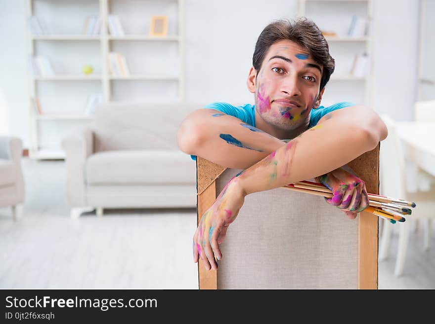 The young funny artist working on new painting in his studio