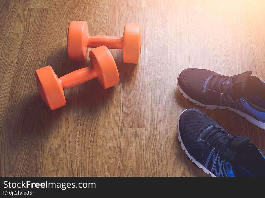 Sneakers and dumbbells fitness on a wooden background. Different tools for sport