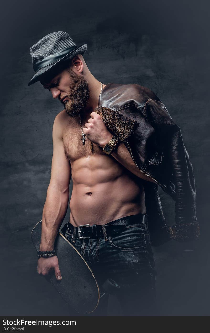 Shirtless bearded male holds skateboard.