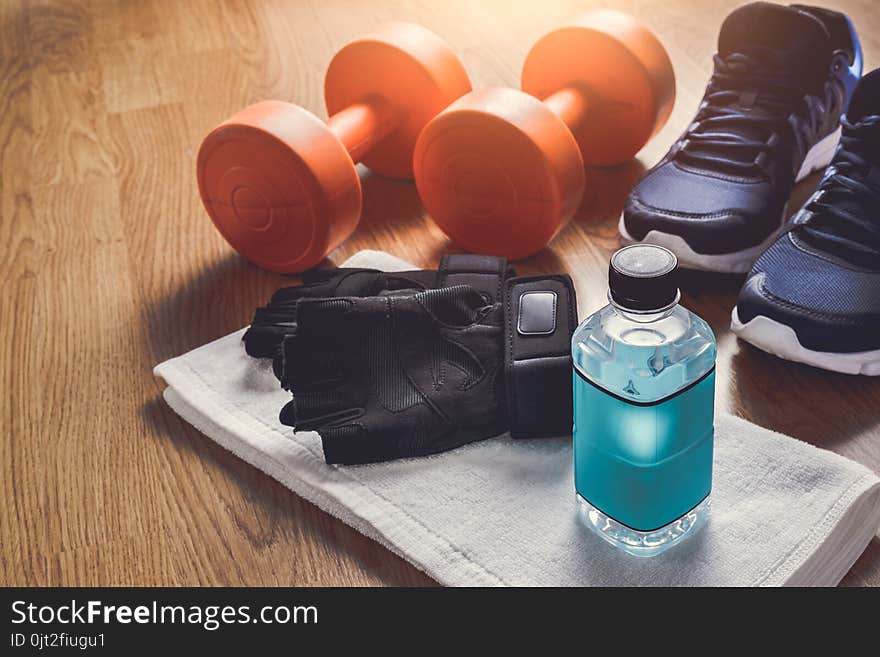 Fitness equipment. Sneakers, water, protective gloves on wooden background. Fitness equipment. Sneakers, water, protective gloves on wooden background