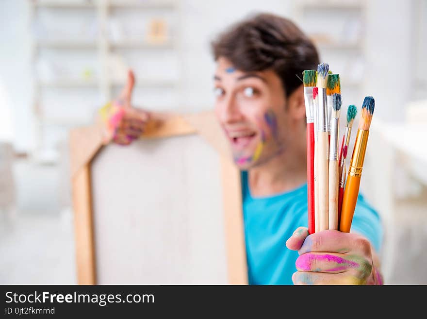 The young funny artist working on new painting in his studio