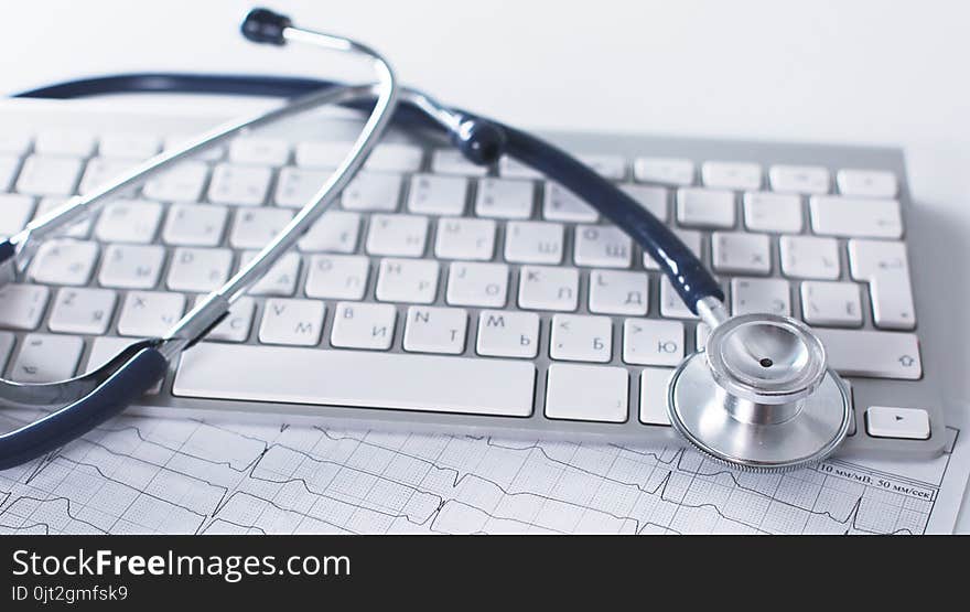 A stethoscope is on the keyboard of a computer.