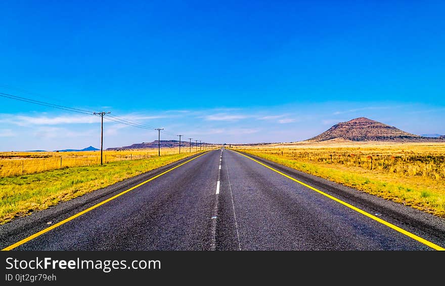 Long Straight Road through the Endless wide open landscape of the semi desert Karoo Region in Free State and Eastern Cape province