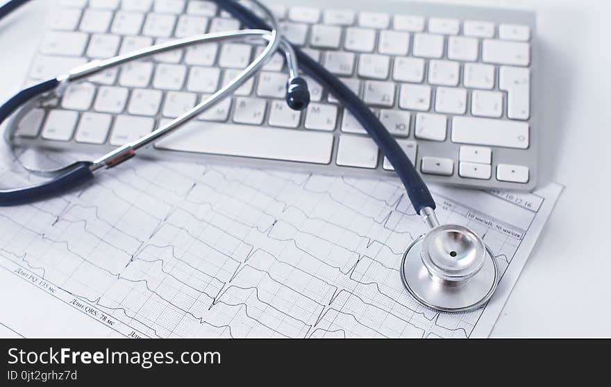 A stethoscope is on the keyboard of a computer.