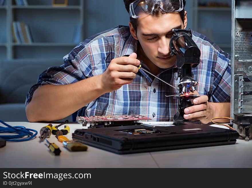 The repairman trying to repair laptop with miscroscope