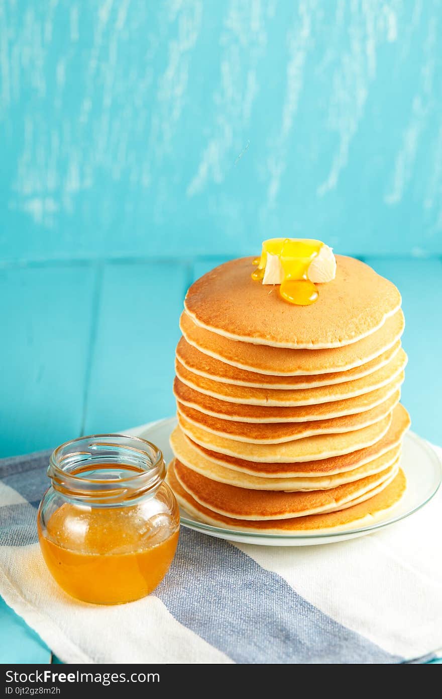 Vertical photo of stack of pancake with honey and butter