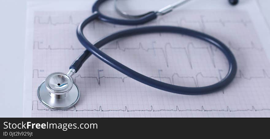 Stethoscope on cardiogram concept for heart care on the desk.blue toned images.