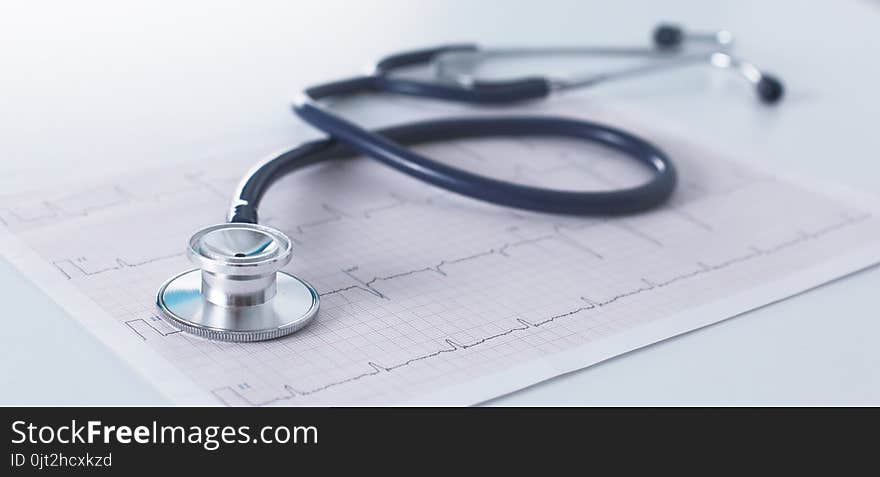 Stethoscope on cardiogram concept for heart care on the desk.blue toned images.