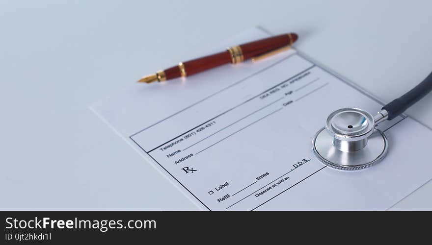 Doctor`s workspace working table with patient`s discharge blank paper form, medical prescription, stethoscope on desk.