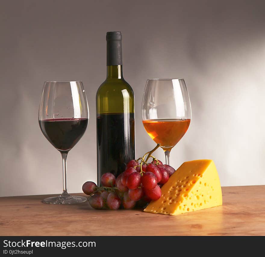 Still life with glass and bottle of wine, cheese and grapes.