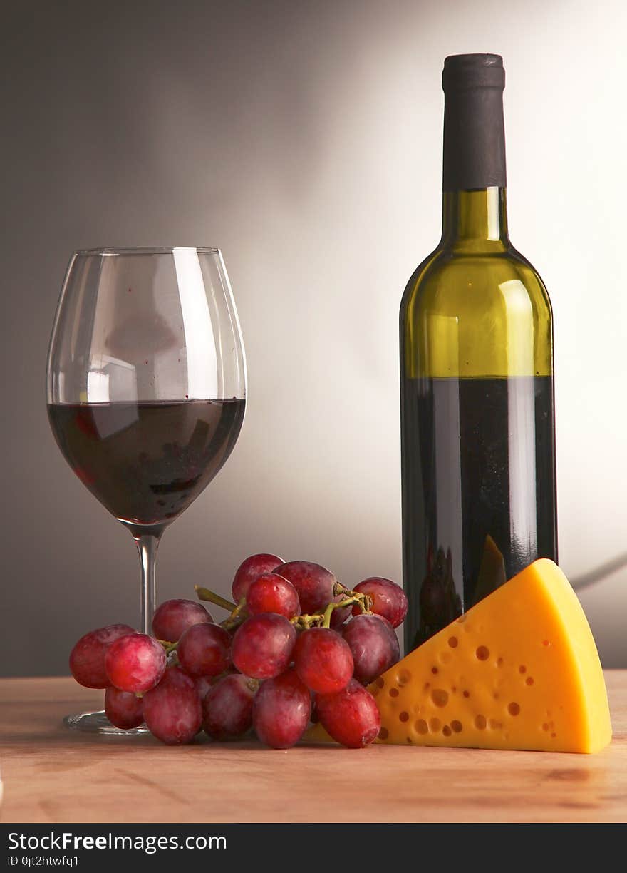 Still life with glass and bottle of wine, cheese and grapes.