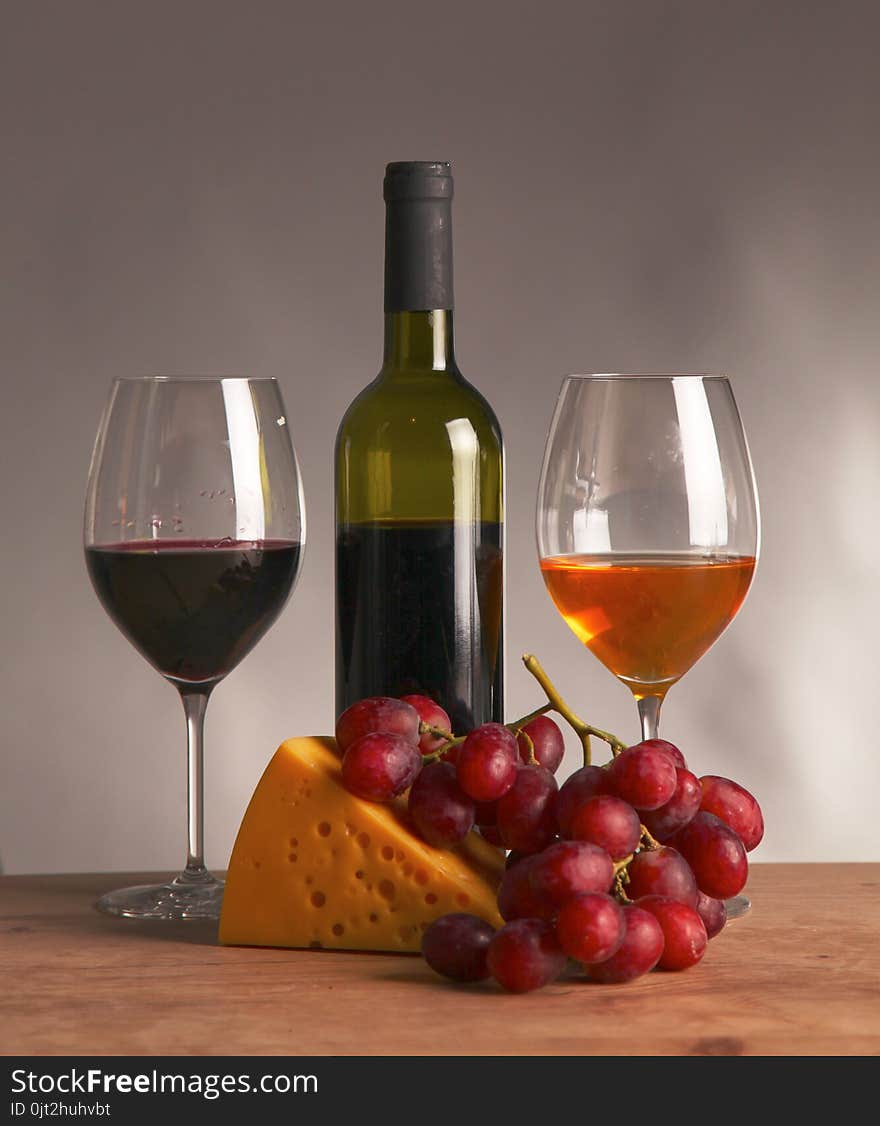 Still life with glass and bottle of wine, cheese and grapes.