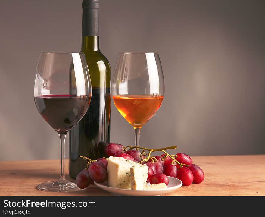 Still life with glass and bottle of wine, cheese and grapes.