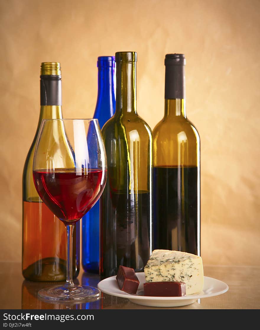 Still life with glass and bottle of wine, cheese and grapes.