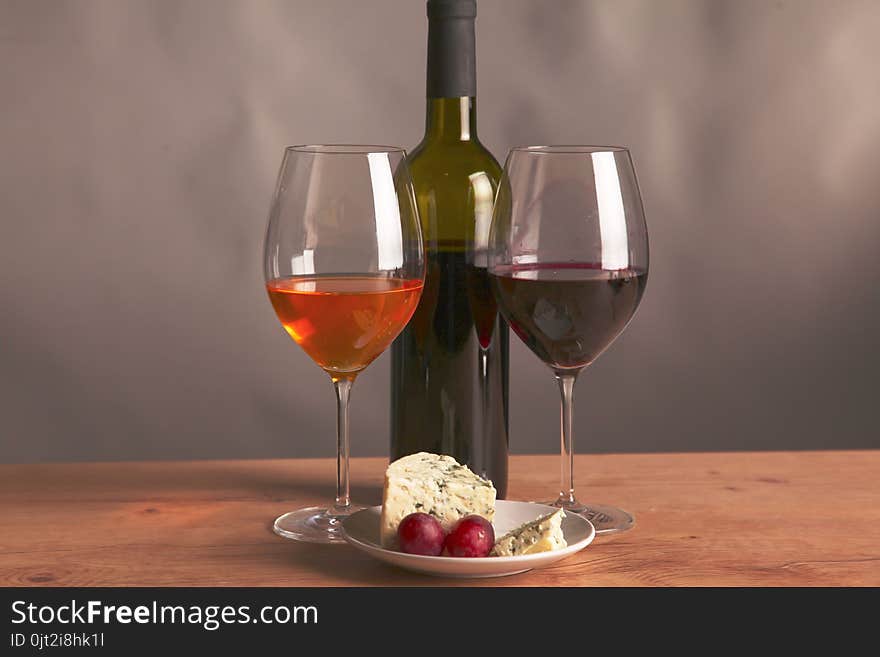 Still life with glass and bottle of wine, cheese and grapes.