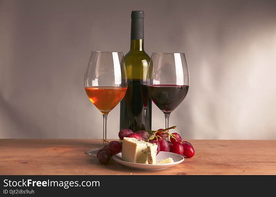 Still life with glass and bottle of wine, cheese and grapes.