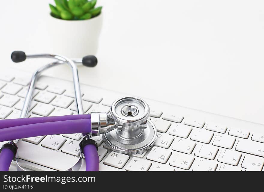 A stethoscope is on the keyboard of a computer.