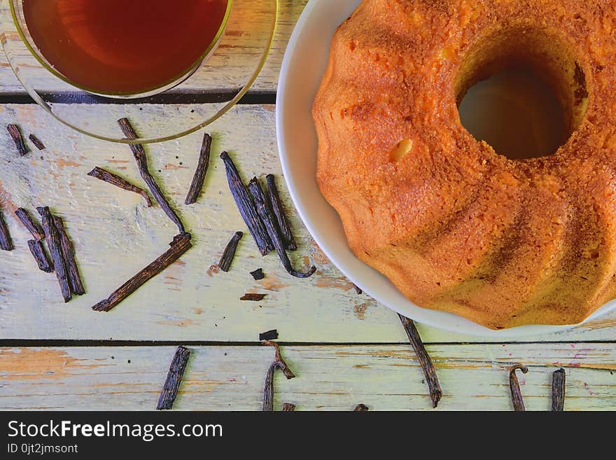 Old fashioned sand cake with cup of black tea and pieces of vanilla on wooden background. Egg-yolk sponge cake on rustic white background. Top view. Flat design.