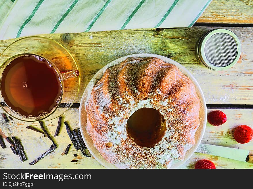 Old fashioned sand cake with cup of black tea and pieces of vanilla on wooden background. Egg-yolk sponge cake with stawberries on rustic white background. Top view. Flat design.