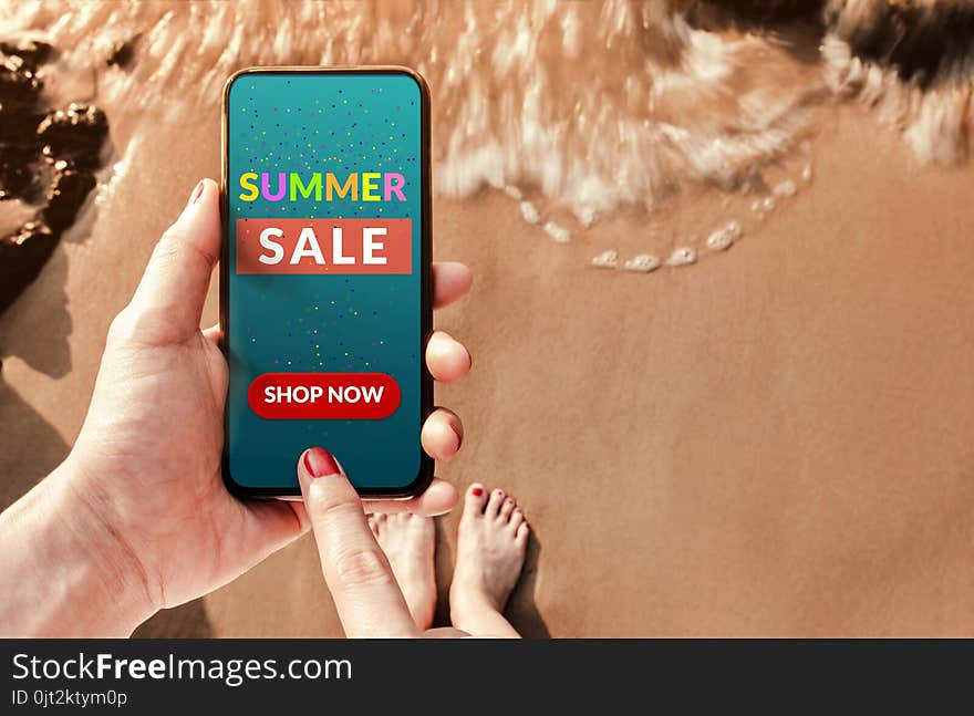 Summer Sale Promotional Concept. Top view of Woman Customer using Smart Phone with Advertising Deals on the Screen at Summer Beach for Online Shopping
