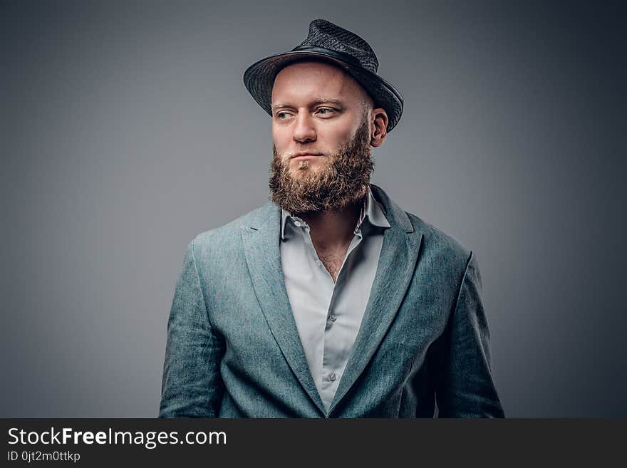 Stylish bearded male in a suit and felt hat on grey vignette background. Stylish bearded male in a suit and felt hat on grey vignette background.