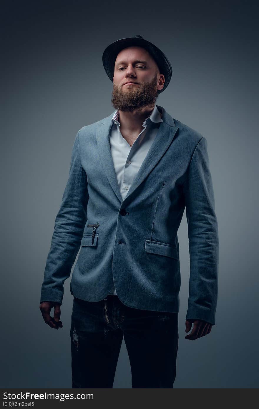 Stylish bearded male in a suit and felt hat on grey vignette background. Stylish bearded male in a suit and felt hat on grey vignette background.