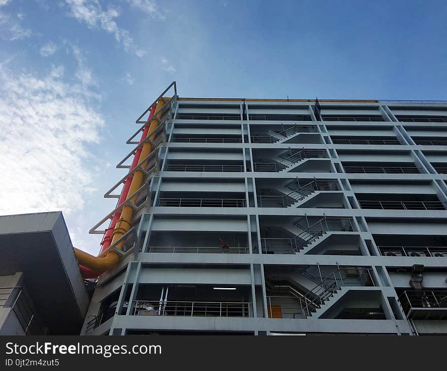 Architecture building, It has stair every floor. orange and yellow pipe side the building. cirrocumulus clouds and blue sky. industrial heathy and medical. Architecture building, It has stair every floor. orange and yellow pipe side the building. cirrocumulus clouds and blue sky. industrial heathy and medical