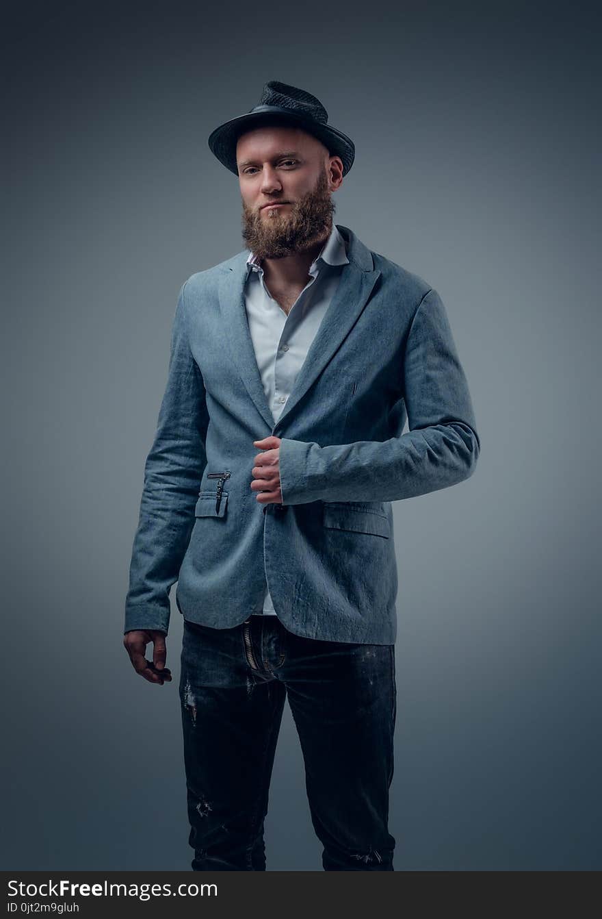 Stylish bearded male in a suit and felt hat on grey vignette background. Stylish bearded male in a suit and felt hat on grey vignette background.