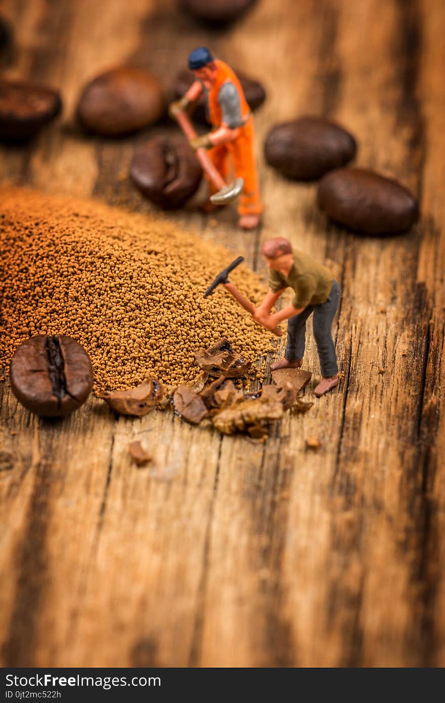 Miniature figures working on instant coffee macro photography on wood table. Miniature figures working on instant coffee macro photography on wood table