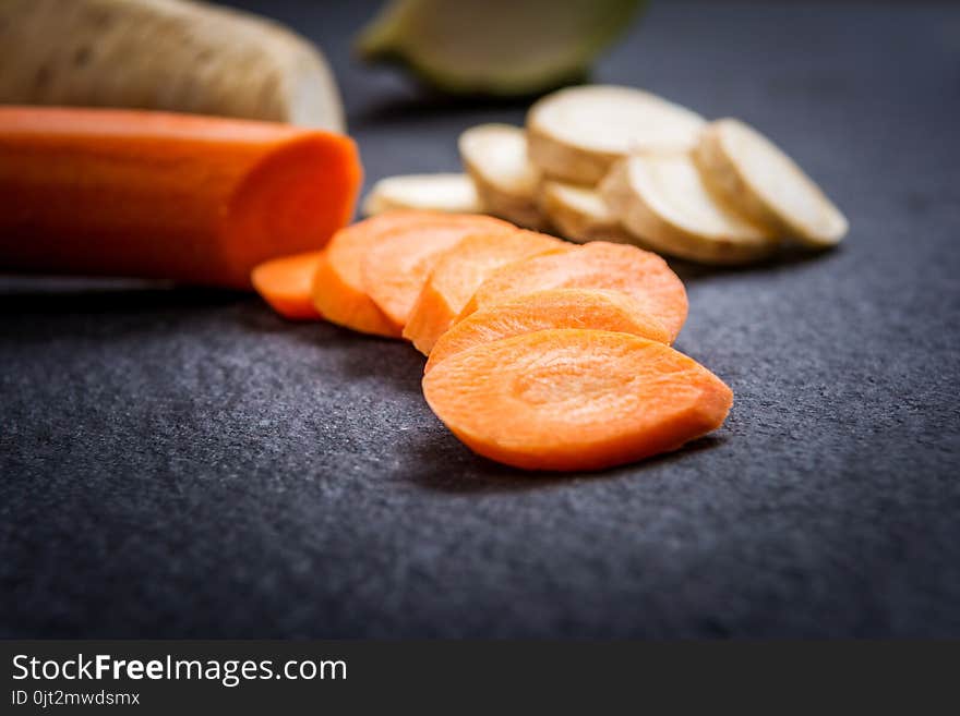 Cuts of carrot and parsley on dark stone table