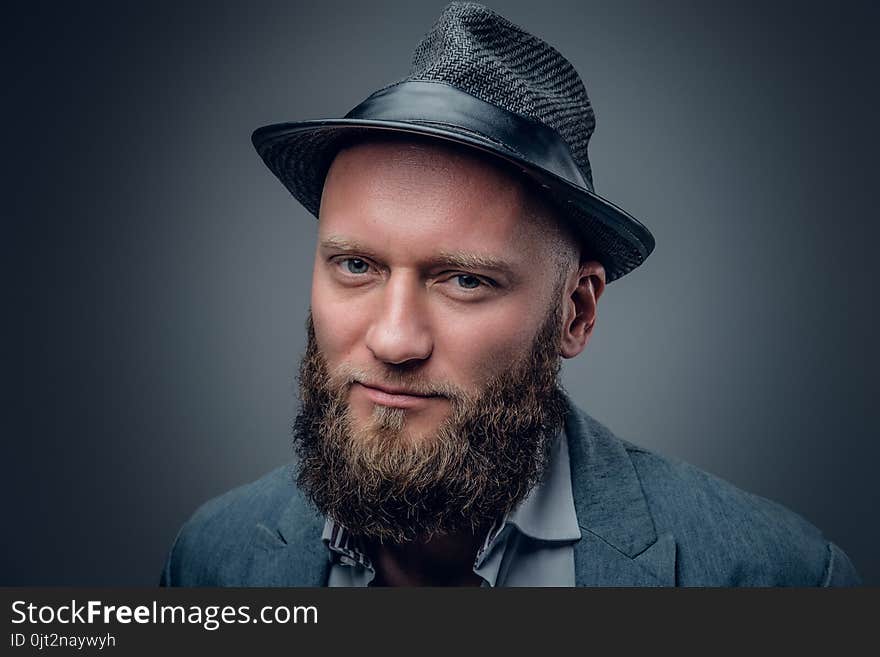 Close up studio portrait of bearded male in a felt hat on grey background. Close up studio portrait of bearded male in a felt hat on grey background.