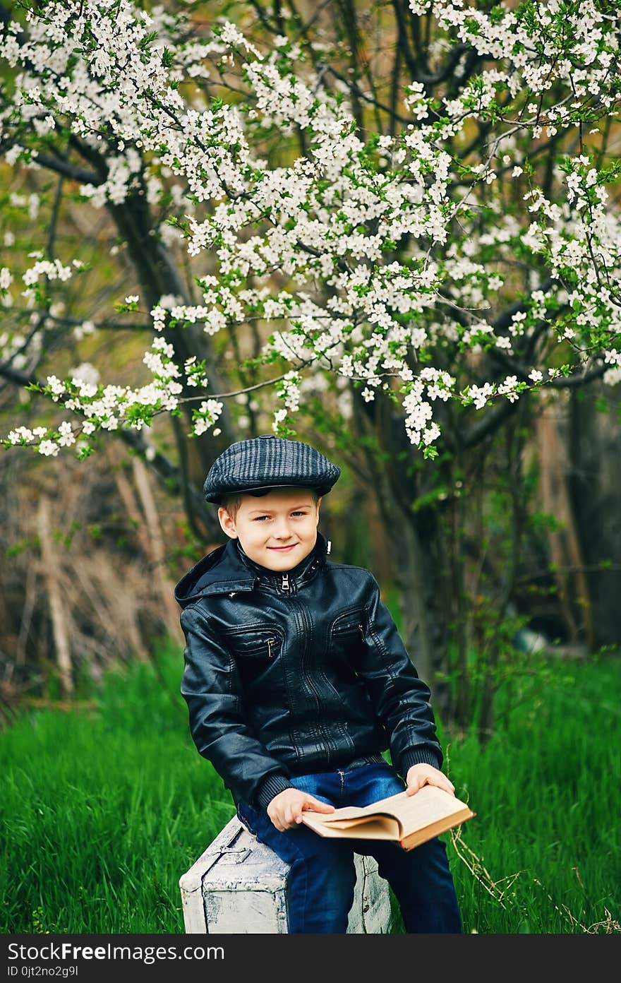 Boy in the spring flowering garden with a book in his hands. Boy in the spring flowering garden with a book in his hands