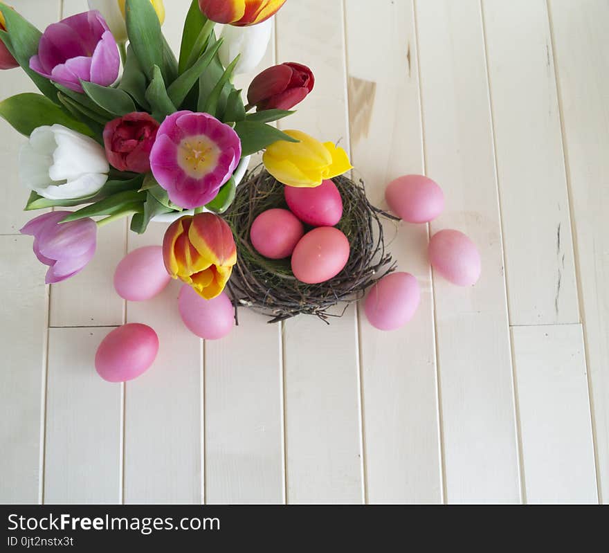 Easter. Pink easter eggs and tulips lie on a wooden background. Flat lay. Bird`s Nest. March 8. Pastel shades of pink. Wooden background. Conceptual photo. St. Patrick`s Day. Easter pink rabbit.