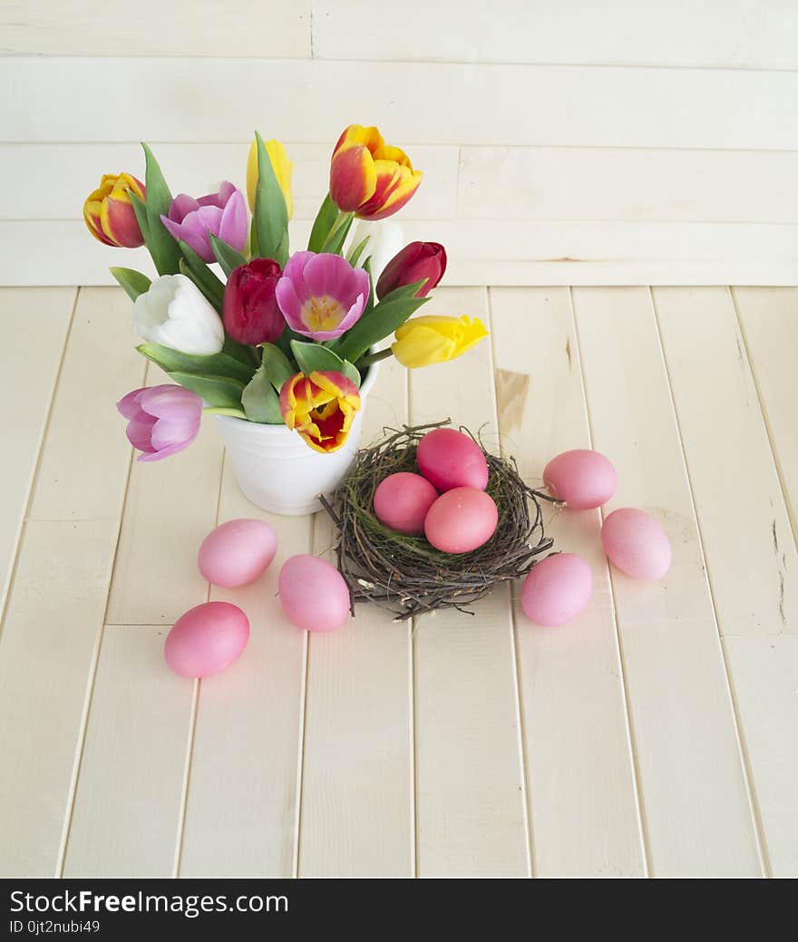 Easter. Pink easter eggs and tulips lie on a wooden background. Flat lay. Bird`s Nest. March 8. Pastel shades of pink. Wooden background. Conceptual photo. St. Patrick`s Day. Easter pink rabbit.