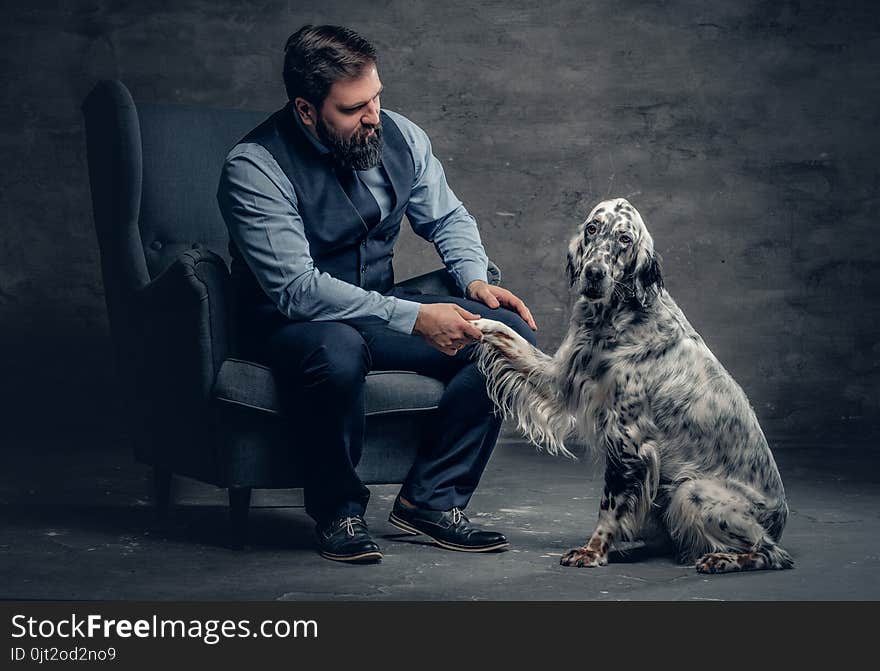 Portrait of stylish bearded male sits on a chair and the Irish setter dog.