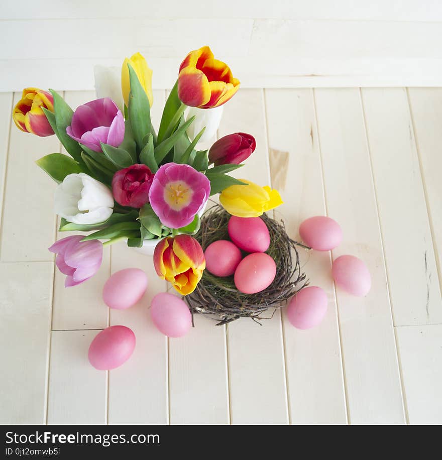 Easter. Pink easter eggs and tulips lie on a wooden background. Flat lay. Bird`s Nest. March 8. Pastel shades of pink. Wooden background. Conceptual photo. St. Patrick`s Day. Easter pink rabbit.