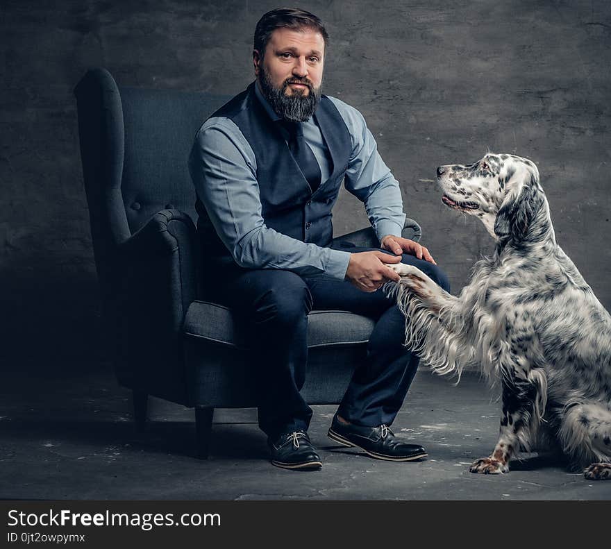 Portrait of stylish bearded male sits on a chair and the Irish setter dog.