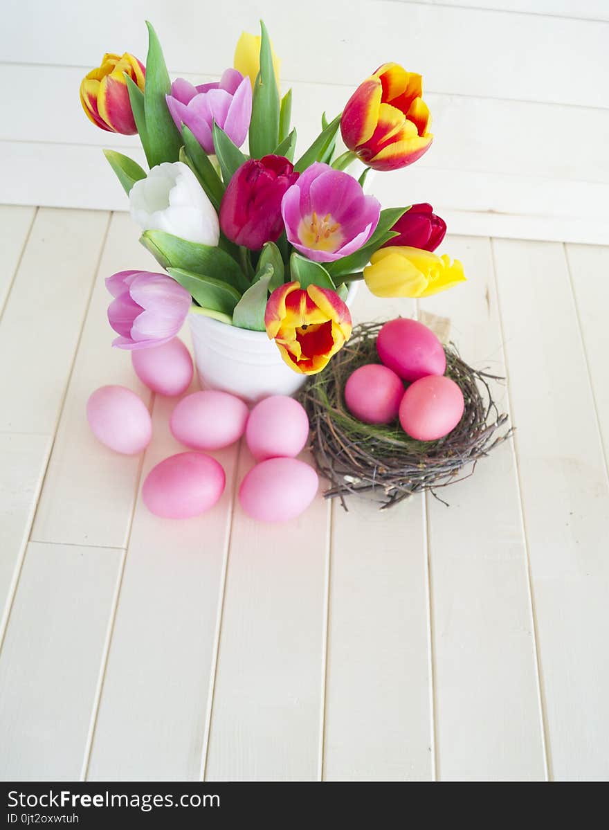 Easter. Pink easter eggs and tulips lie on a wooden background. Flat lay.